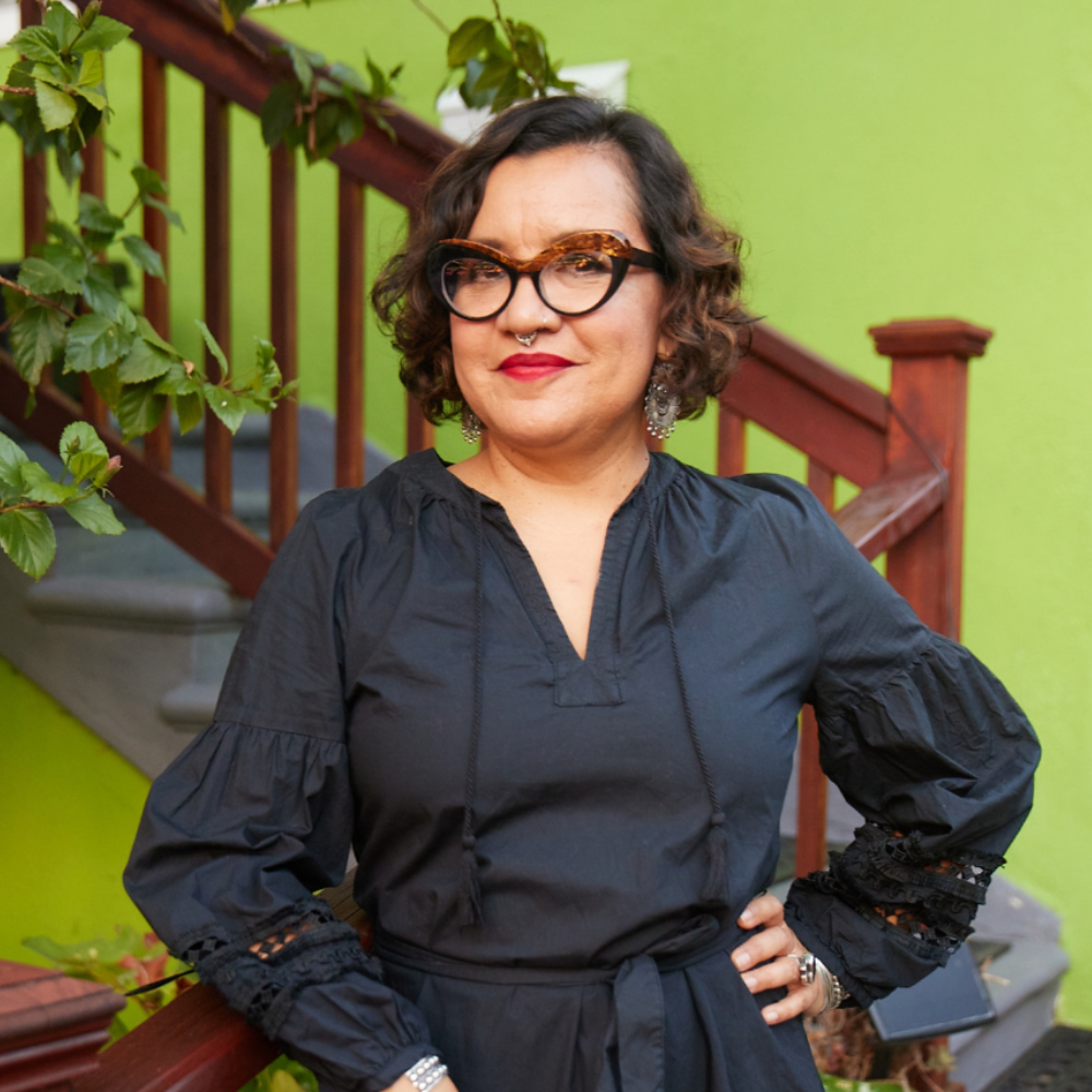 portrait of Martha Gonzales, a latinx individual wearing glasses and a black dress