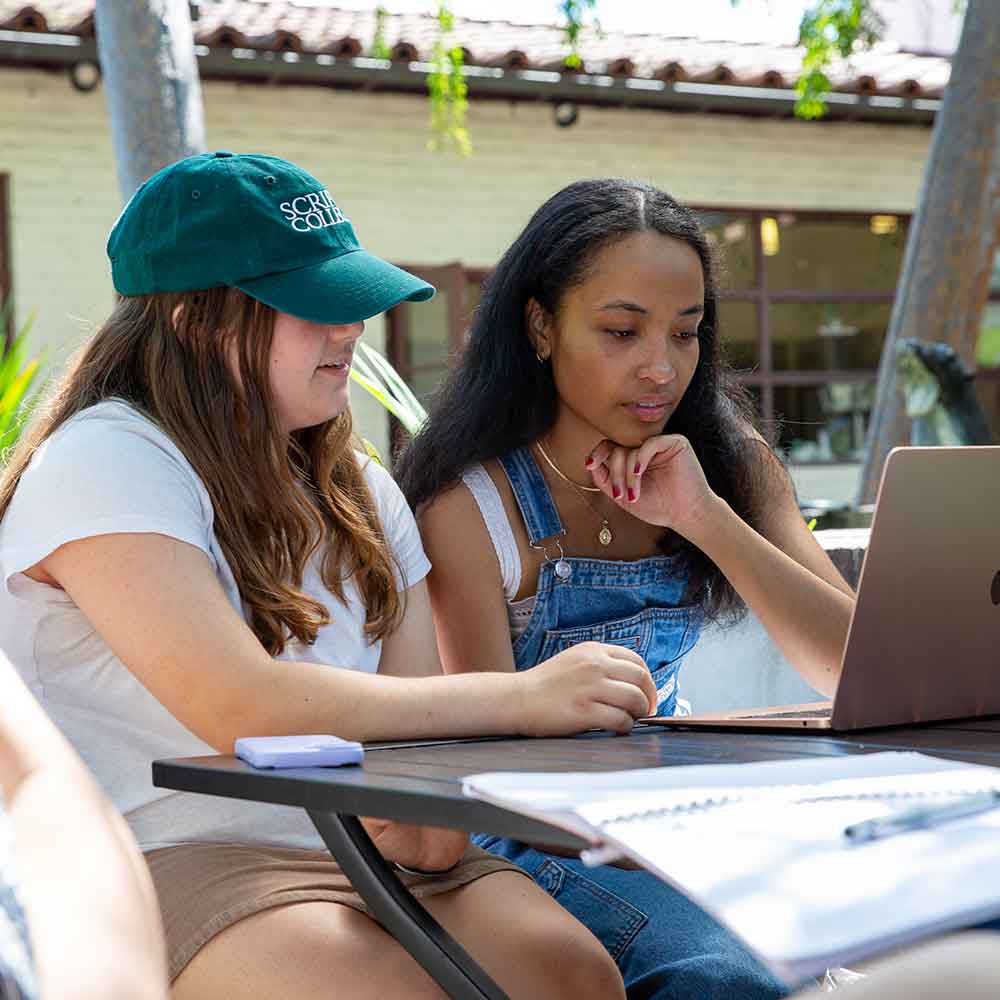 Two students outside looking at a laptop
