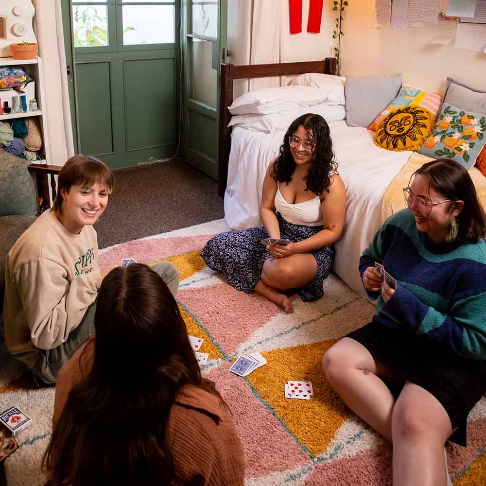 Four students sitting on the floor in a residence hall room